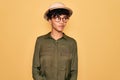 Young beautiful african american tourist woman wearing glasses and explorer hat smiling looking to the side and staring away Royalty Free Stock Photo