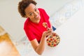 Young beautiful african american woman with afro hair eating healthy wholemeal cereals and berries as healthy breakfast