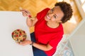 Young beautiful african american woman with afro hair eating healthy wholemeal cereals and berries as healthy breakfast