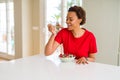 Young beautiful african american woman with afro hair eating healthy wholemeal cereals and berries as healthy breakfast Royalty Free Stock Photo