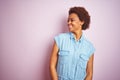 Young beautiful african american woman with afro hair over isolated pink background looking away to side with smile on face, Royalty Free Stock Photo