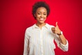 Young beautiful african american woman with afro hair over isolated red background doing happy thumbs up gesture with hand Royalty Free Stock Photo