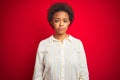 Young beautiful african american woman with afro hair over isolated red background with serious expression on face Royalty Free Stock Photo