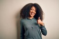 Young beautiful african american woman with afro hair standing over isolated background doing happy thumbs up gesture with hand Royalty Free Stock Photo