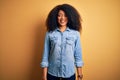 Young beautiful african american woman with afro hair standing over yellow isolated background with a happy and cool smile on face Royalty Free Stock Photo