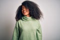 Young beautiful african american woman with afro hair wearing green winter sweater looking away to side with smile on face, Royalty Free Stock Photo