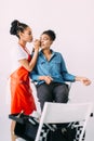 Young beautiful African American woman applying professional make-up by African make-up artist. Studio shoot Royalty Free Stock Photo