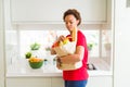 Young beautiful african american woman holding paper bag full of fresh healthy groceries and picking vegetables Royalty Free Stock Photo