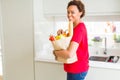 Young beautiful african american woman holding paper bag full of fresh healthy groceries and picking vegetables Royalty Free Stock Photo