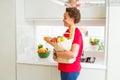 Young beautiful african american woman holding paper bag full of fresh healthy groceries and picking vegetables Royalty Free Stock Photo