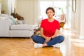 Young beautiful african american woman sitting on the floor at home Relaxed with serious expression on face Royalty Free Stock Photo