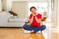 Young beautiful african american woman sitting on the floor at home sleeping tired dreaming and posing with hands together while Royalty Free Stock Photo