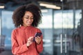 Young beautiful African American woman uses the phone, business woman holds a smartphone in her hands, uses an Royalty Free Stock Photo