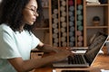 Young beautiful african american woman using her laptop while sitting in chair at her working place Royalty Free Stock Photo