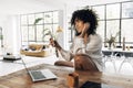 Young beautiful African American woman video calling a friend in a bright beautiful loft apartment in the morning Royalty Free Stock Photo