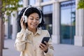 Young beautiful African American woman walking in the city wearing headphones smiling listening to music and audio books Royalty Free Stock Photo