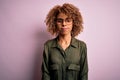 Young beautiful african american woman wearing casual shirt and glasses over pink background with serious expression on face Royalty Free Stock Photo