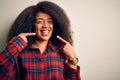 Young beautiful african american woman wearing casual shirt over isolated background smiling cheerful showing and pointing with Royalty Free Stock Photo