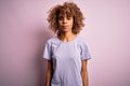 Young beautiful african american woman wearing casual t-shirt standing over pink background with serious expression on face Royalty Free Stock Photo