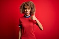 Young beautiful african american woman wearing casual t-shirt standing over red background doing happy thumbs up gesture with hand Royalty Free Stock Photo