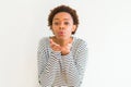 Young beautiful african american woman wearing stripes sweater over white background looking at the camera blowing a kiss with Royalty Free Stock Photo