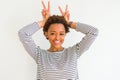 Young beautiful african american woman wearing stripes sweater over white background Posing funny and crazy with fingers on head Royalty Free Stock Photo