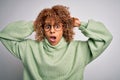 Young beautiful african american woman wearing turtleneck sweater and glasses Crazy and scared with hands on head, afraid and Royalty Free Stock Photo