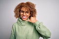 Young beautiful african american woman wearing turtleneck sweater and glasses smiling doing phone gesture with hand and fingers Royalty Free Stock Photo