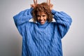 Young beautiful african american woman wearing turtleneck sweater over white background Posing funny and crazy with fingers on Royalty Free Stock Photo