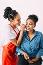 Young beautiful African American woman applying professional make-up by African make-up artist. Studio shoot Royalty Free Stock Photo