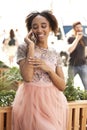 Young beautiful African girl talking on cell phone outdoors in pink dress Royalty Free Stock Photo