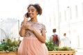 Young beautiful African girl talking on cell phone outdoors in pink dress Royalty Free Stock Photo