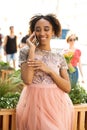 Young beautiful African girl talking on cell phone outdoors in pink dress Royalty Free Stock Photo