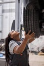 Young beautiful african mechanic woman adjusting the tire at repair garage Royalty Free Stock Photo