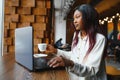 Young beautiful Afro-American businesswoman using laptop while working in cafe Royalty Free Stock Photo