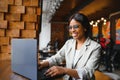 Young beautiful Afro-American businesswoman using laptop while working in cafe Royalty Free Stock Photo