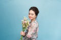 Young beautiful Aisa girl holding a bouquet on blue background