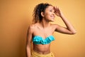 Young beautiful american woman on vacation wearing bikini over isolated yellow background very happy and smiling looking far away Royalty Free Stock Photo
