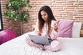 Young beautiful arab woman using laptop drinking coffee at bedroom Royalty Free Stock Photo