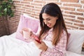 Young beautiful arab woman using smartphone drinking coffee at bedroom Royalty Free Stock Photo