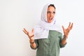 Young beautiful Arab woman wearing traditional Muslim hijab over isolated background crazy and mad shouting and yelling with Royalty Free Stock Photo