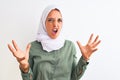 Young beautiful Arab woman wearing traditional Muslim hijab over isolated background crazy and mad shouting and yelling with Royalty Free Stock Photo