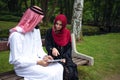 Young beautiful Arabian couple casual and hijab, Abaya, taking a selfie on the lawn in summer park.