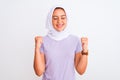 Young beautiful arabian girl wearing hijab standing over isolated white background excited for success with arms raised and eyes