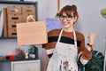 Young beautiful artist woman holding wooden case pointing thumb up to the side smiling happy with open mouth Royalty Free Stock Photo