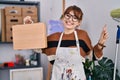 Young beautiful artist woman holding wooden case smiling happy pointing with hand and finger to the side Royalty Free Stock Photo