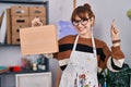 Young beautiful artist woman holding wooden case smiling with an idea or question pointing finger with happy face, number one Royalty Free Stock Photo