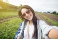 Cheerful young Asian woman traveler with backpack taking a photo or selfie