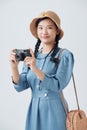 Young beautiful Asian backpack traveler woman using digital compact camera and smile, looking at copy space Royalty Free Stock Photo