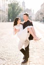 Young beautiful Asian bride and groom on the wedding walk through the streets of old European city. Man holding woman on Royalty Free Stock Photo